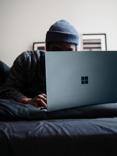 人在灰色的针织帽使用微软表面计算机在钴蓝色的颜色
